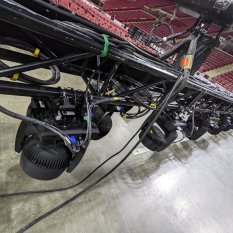 Moving lights being hung from truss in an arena