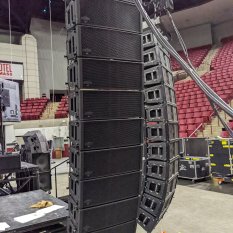 Line array loudspeakers being hung in an arena